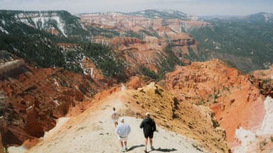 Three people stand on an outcrop of rock overlooking a canyon at Cedar Breaks National Monument