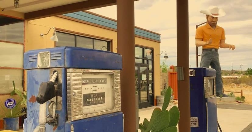 A gas station pump with a large statue in the background at the Station in Joshua Tree, Califronia